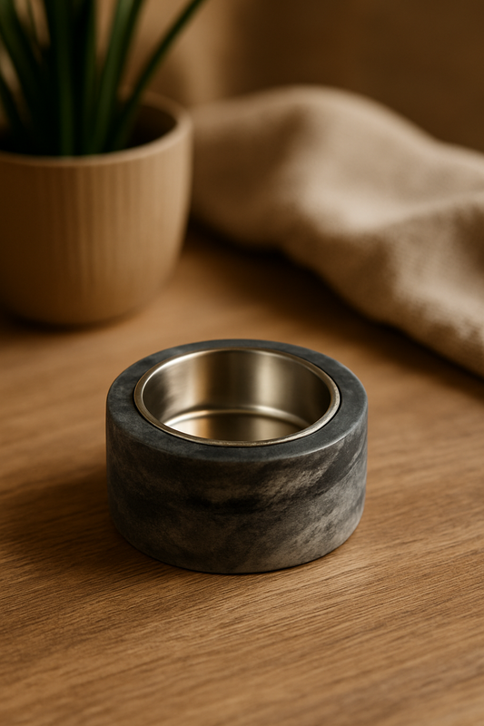 Marble-textured ring with metallic interior on a wooden surface, next to a plant and fabric.