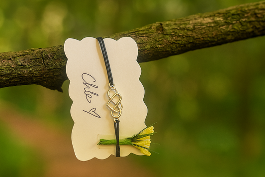 Necklace with a floral pendant on a white card, hanging from a branch with a blurred green background made from natural hemp